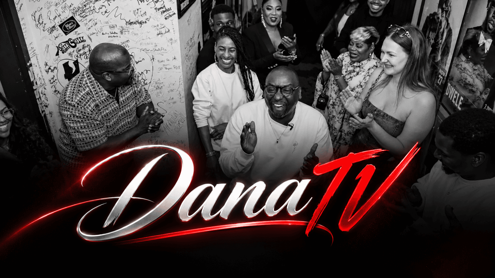 Dana Soréy laughing and clapping with friends and guest artists in a packed backstage hallway, in black and white, with the Dana TV logo in silver and red
